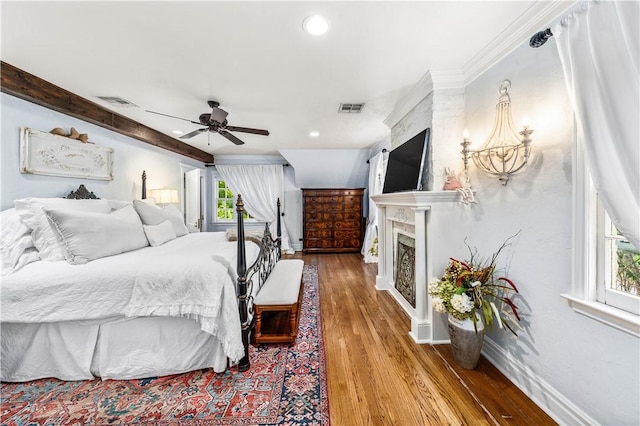 bedroom featuring ceiling fan, a large fireplace, wood-type flooring, and multiple windows