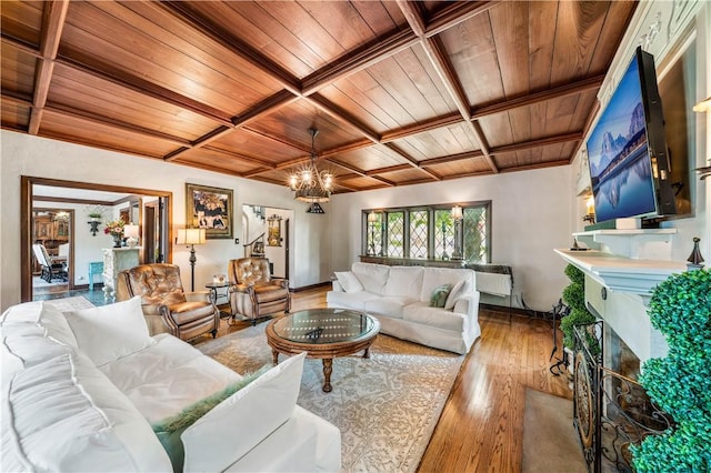 living room with beam ceiling, light hardwood / wood-style flooring, wooden ceiling, and an inviting chandelier