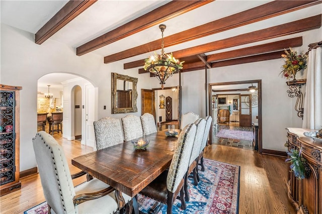 dining space with a notable chandelier, beam ceiling, and light hardwood / wood-style flooring