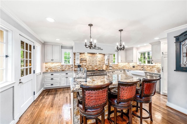 kitchen featuring plenty of natural light, a center island, decorative light fixtures, and light hardwood / wood-style flooring