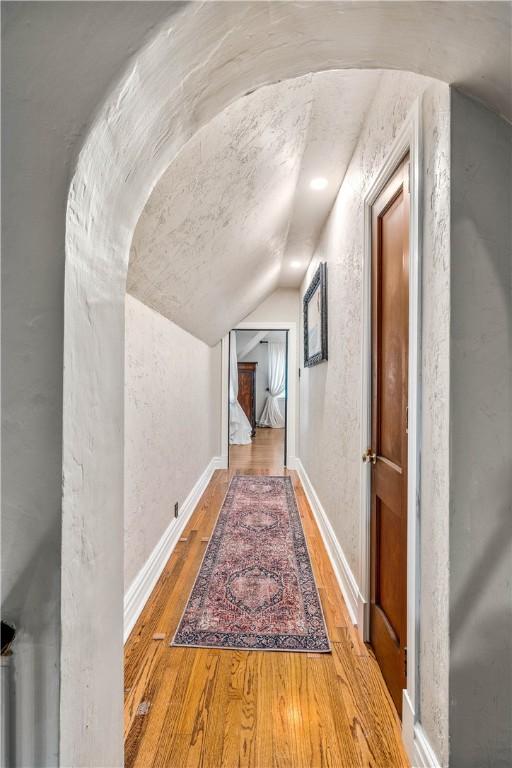 hallway with lofted ceiling and hardwood / wood-style flooring