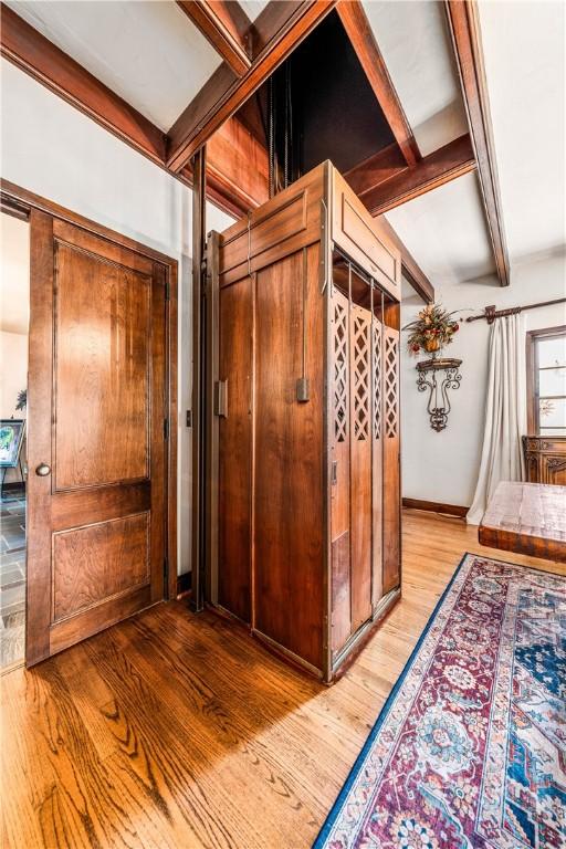 corridor with beam ceiling and hardwood / wood-style flooring