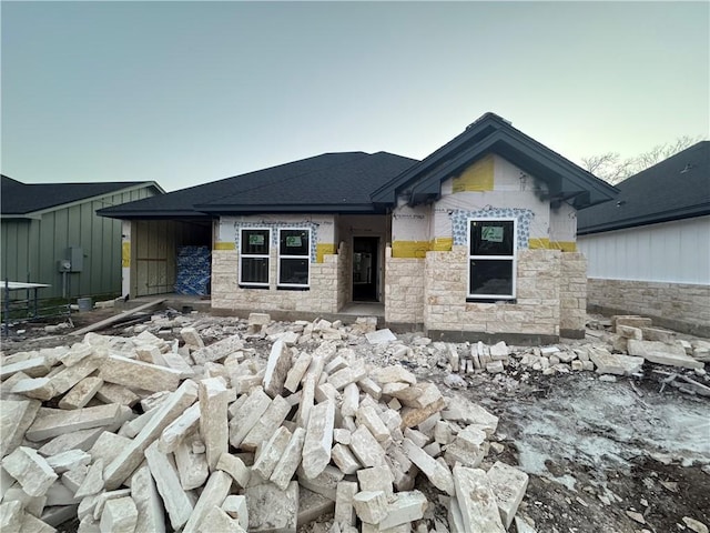 view of front of house featuring stone siding and a shingled roof