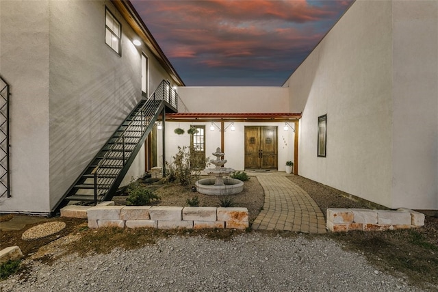 exterior entry at dusk featuring stucco siding