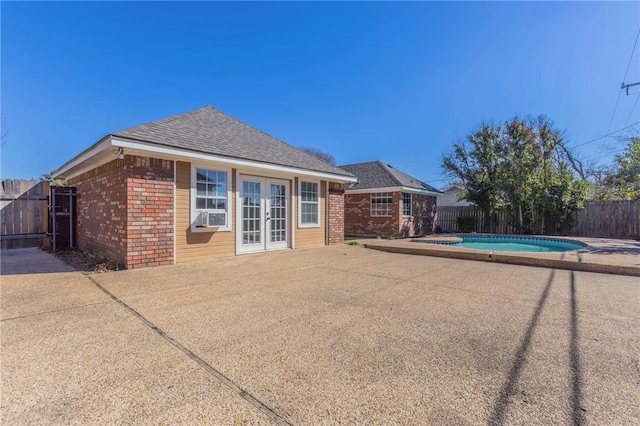 rear view of property featuring french doors, a fenced in pool, a patio area, and cooling unit