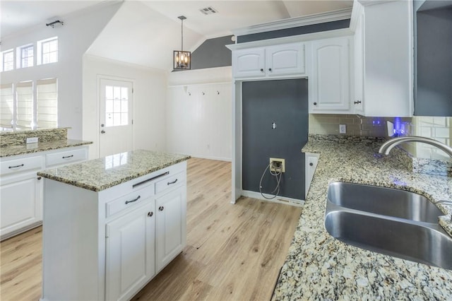 kitchen with white cabinetry, lofted ceiling, sink, light hardwood / wood-style floors, and light stone countertops