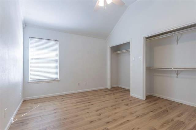 unfurnished bedroom with lofted ceiling, ceiling fan, ornamental molding, light hardwood / wood-style floors, and two closets