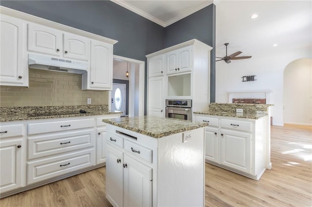 kitchen with dark stone countertops, white cabinets, oven, a center island, and black electric cooktop