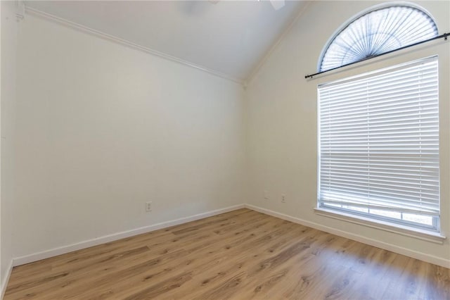 empty room featuring crown molding, vaulted ceiling, ceiling fan, and light wood-type flooring