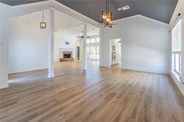 unfurnished living room with hardwood / wood-style flooring, high vaulted ceiling, ceiling fan with notable chandelier, and a fireplace