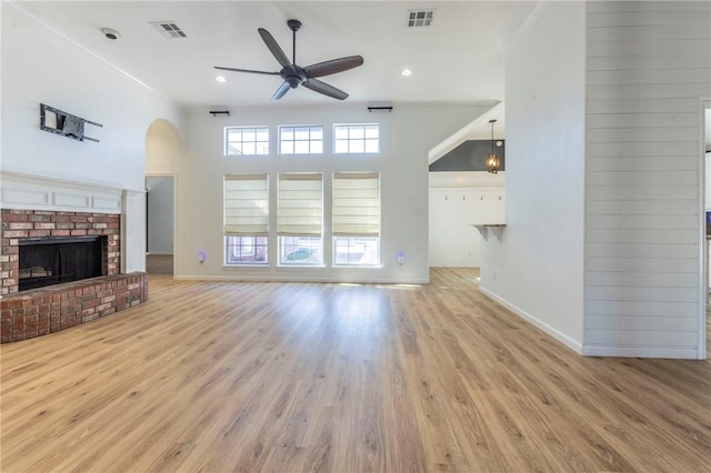 unfurnished living room featuring ceiling fan, a brick fireplace, crown molding, and light hardwood / wood-style floors