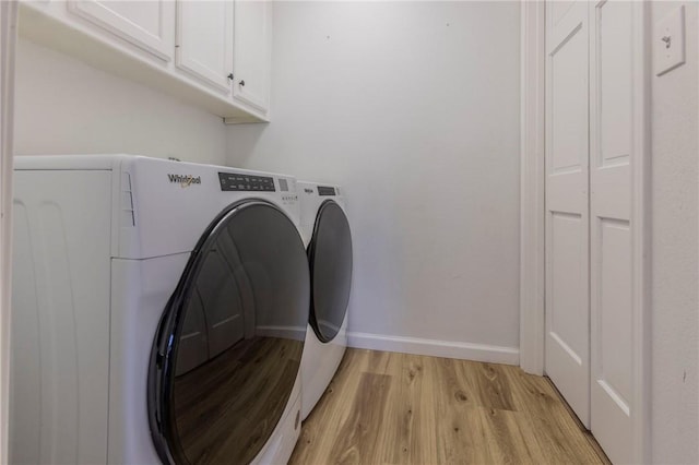 laundry room featuring cabinets, washing machine and clothes dryer, and light hardwood / wood-style flooring