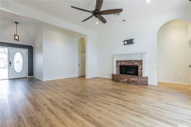 unfurnished living room with crown molding, ceiling fan, a fireplace, and light hardwood / wood-style flooring