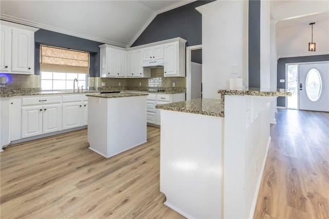 kitchen with stone counters, a center island, sink, and white cabinets