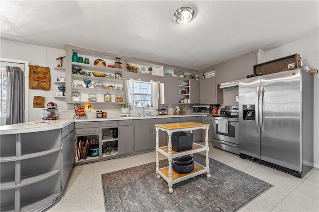 kitchen with sink, gray cabinets, a textured ceiling, and appliances with stainless steel finishes