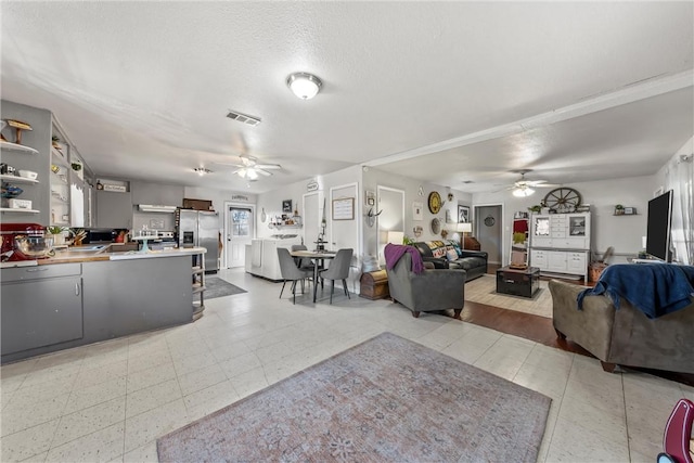 living room with ceiling fan and a textured ceiling