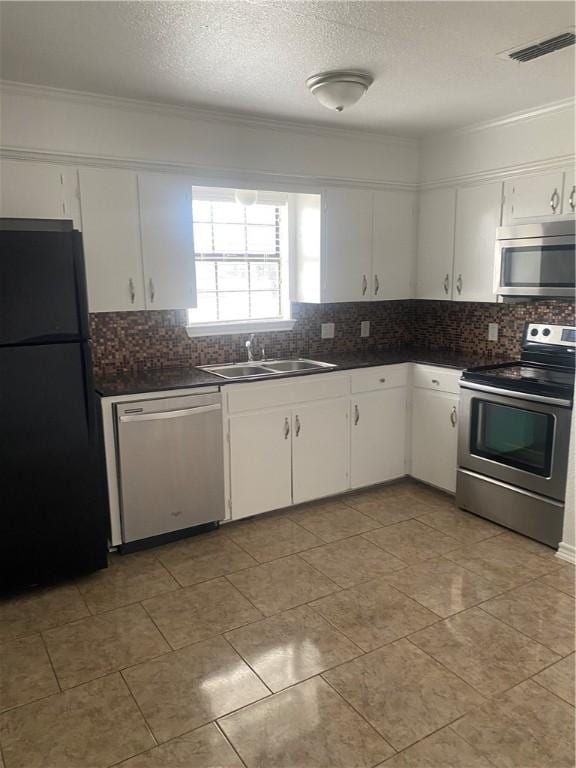 kitchen with stainless steel appliances, dark countertops, visible vents, white cabinets, and a sink