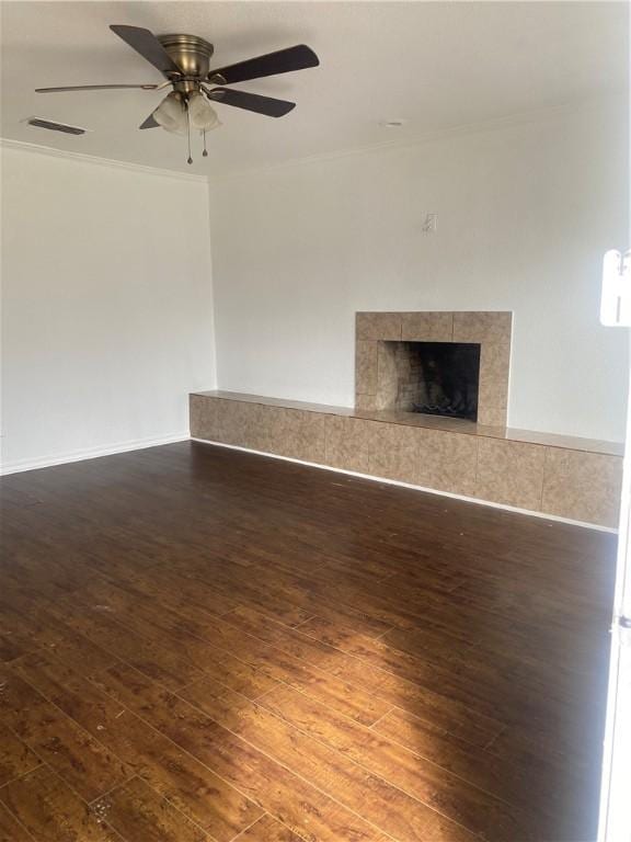 unfurnished living room with visible vents, a ceiling fan, a tiled fireplace, hardwood / wood-style flooring, and crown molding