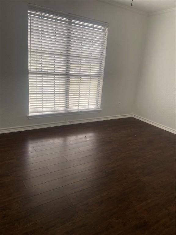 unfurnished room with ornamental molding, dark wood-style flooring, and baseboards