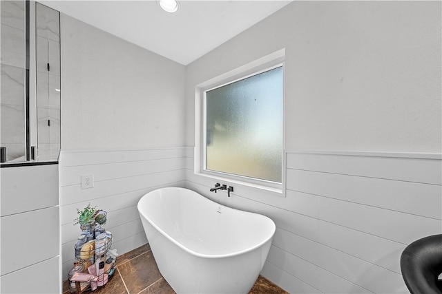 bathroom featuring a washtub, tile patterned flooring, and lofted ceiling