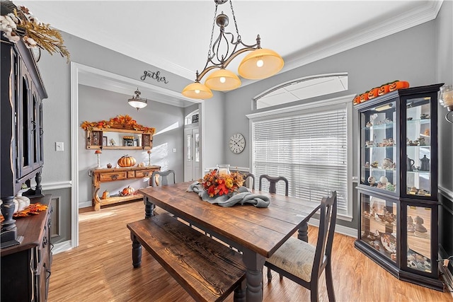 dining space with a chandelier, ornamental molding, and light hardwood / wood-style flooring