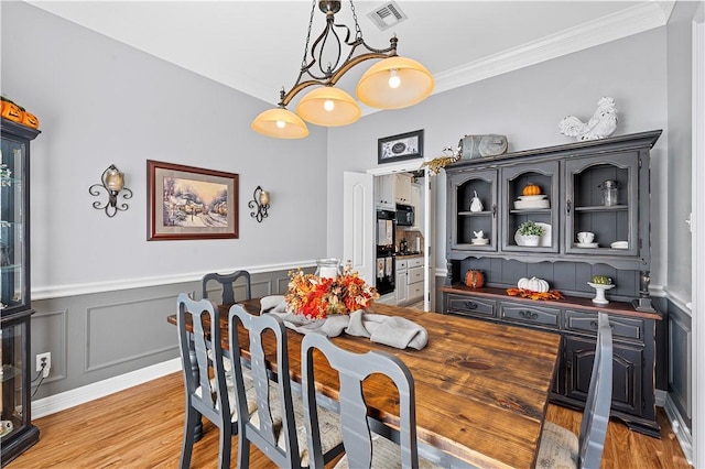 dining area with light wood-type flooring and ornamental molding