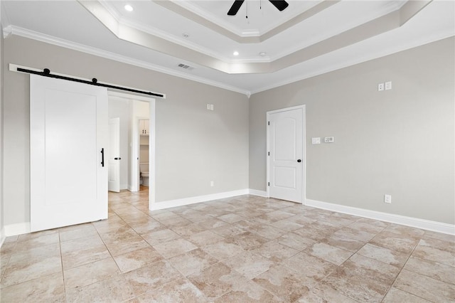 unfurnished room featuring a barn door, a tray ceiling, ceiling fan, and crown molding