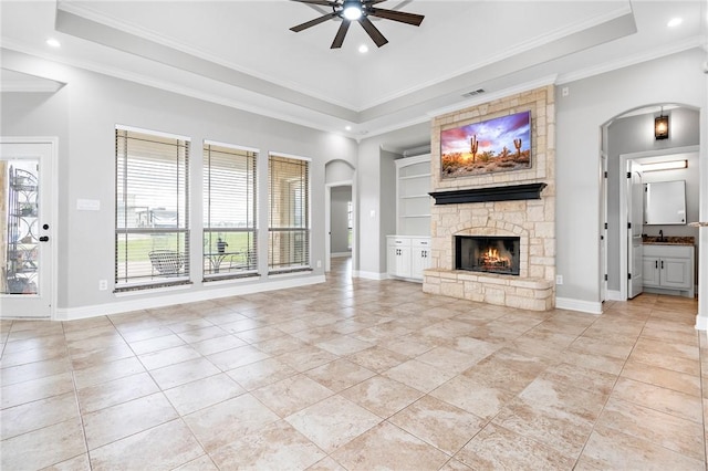 unfurnished living room with ceiling fan, ornamental molding, a fireplace, and a tray ceiling