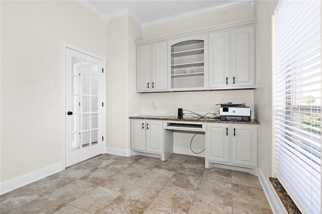 kitchen featuring white cabinets, built in desk, ornamental molding, and dark stone countertops