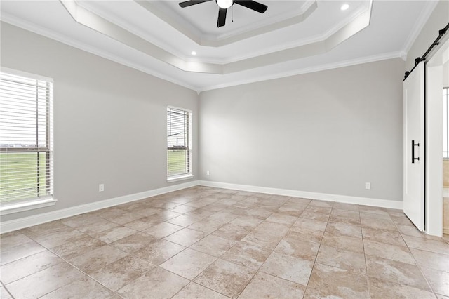 unfurnished room with a barn door, a tray ceiling, ceiling fan, and ornamental molding