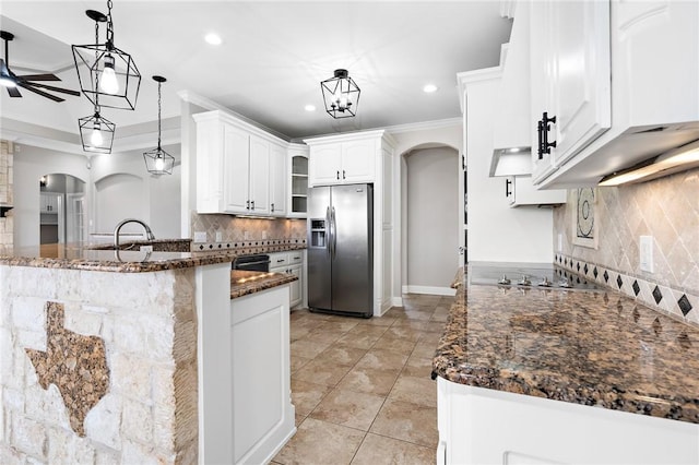 kitchen featuring tasteful backsplash, kitchen peninsula, stainless steel fridge, decorative light fixtures, and white cabinets