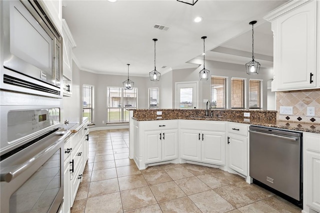 kitchen featuring appliances with stainless steel finishes, backsplash, white cabinetry, and dark stone counters