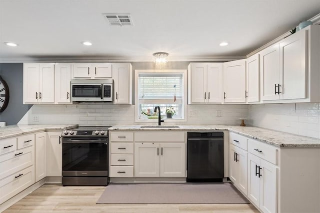 kitchen featuring stainless steel appliances, a sink, visible vents, white cabinets, and light wood-type flooring