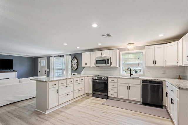 kitchen featuring light wood finished floors, visible vents, a peninsula, stainless steel appliances, and a sink