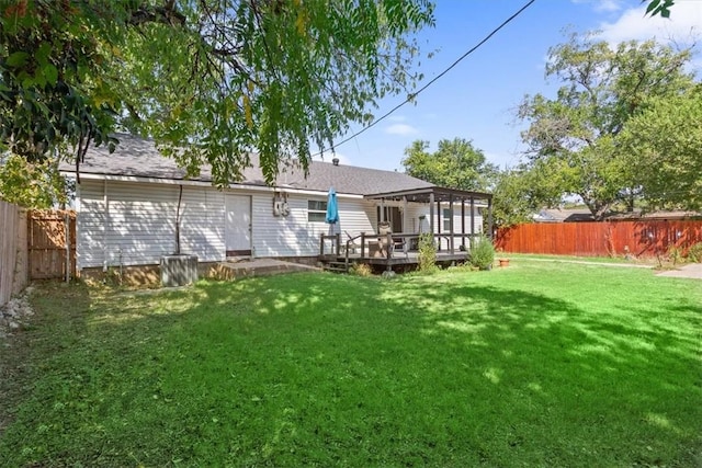 rear view of property featuring a fenced backyard, a lawn, and a deck