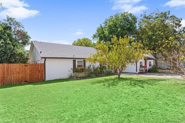 view of front facade featuring a front lawn, roof with shingles, and fence