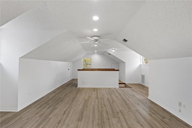 bonus room featuring lofted ceiling, a healthy amount of sunlight, light wood-type flooring, and ceiling fan