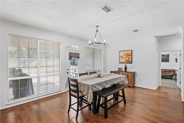 dining space with a chandelier, dark wood-type flooring, a textured ceiling, and ornamental molding