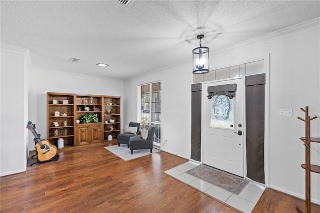 entryway with wood-type flooring, a textured ceiling, and ornamental molding