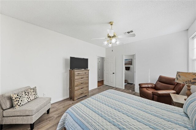 bedroom with ceiling fan, wood-type flooring, and a textured ceiling