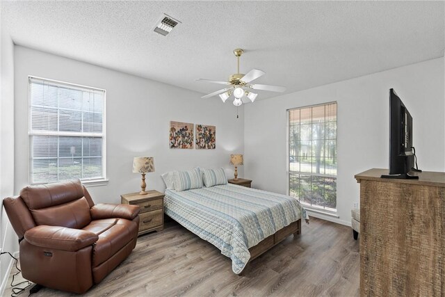 bedroom with multiple windows, hardwood / wood-style flooring, and ceiling fan