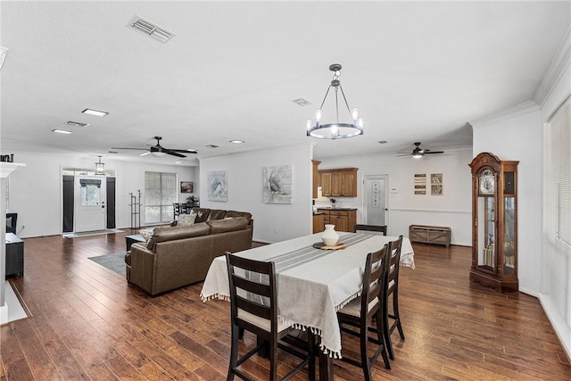 dining area featuring ceiling fan with notable chandelier, dark hardwood / wood-style flooring, and crown molding