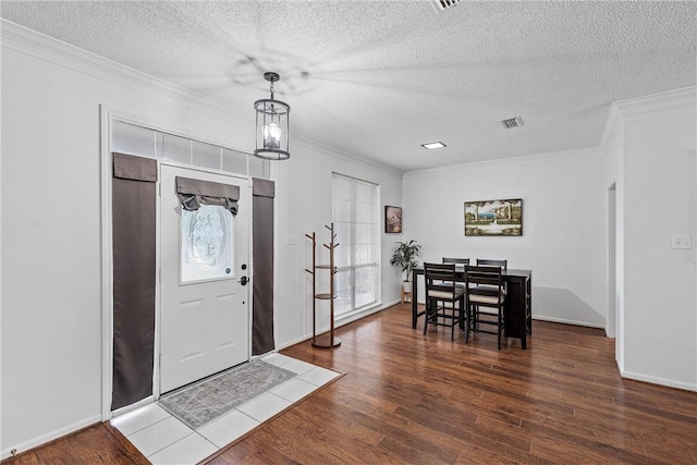 entrance foyer with hardwood / wood-style flooring, a healthy amount of sunlight, ornamental molding, and a textured ceiling