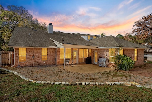 back house at dusk featuring a patio