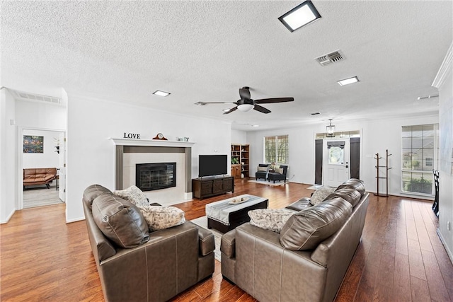 living room featuring hardwood / wood-style floors, a textured ceiling, ceiling fan, and crown molding