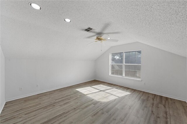 bonus room with hardwood / wood-style floors, ceiling fan, lofted ceiling, and a textured ceiling