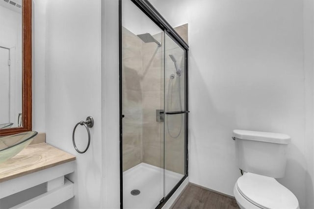 bathroom with hardwood / wood-style flooring, vanity, toilet, and a shower with shower door