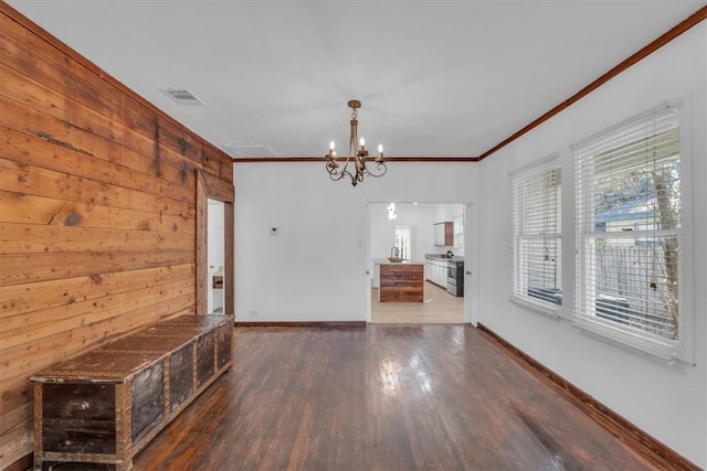 interior space featuring crown molding, wooden walls, dark hardwood / wood-style floors, and a notable chandelier