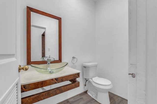 bathroom with hardwood / wood-style floors, vanity, and toilet