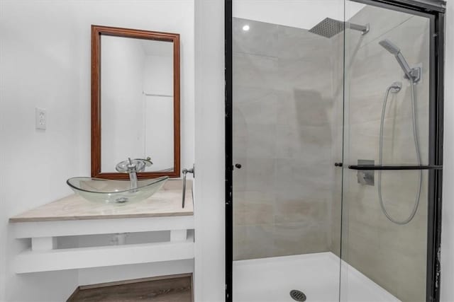 bathroom featuring a shower with door and vanity